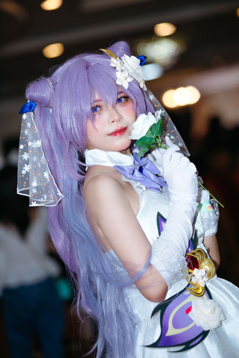 Anime cosplay featuring a character with purple hair, floral accents, and intricate costume details.