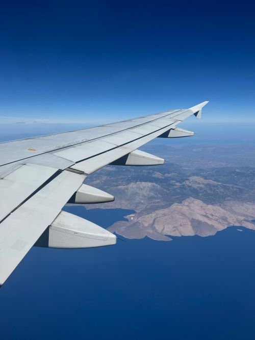 Free Scenic airplane view over Corfu, Greece, showcasing wing and Mediterranean Sea. Stock Photo