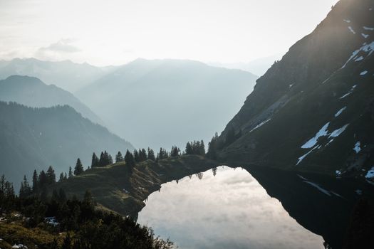 Majestic mountain lake reflecting the sky at sunrise, surrounded by alpine peaks.