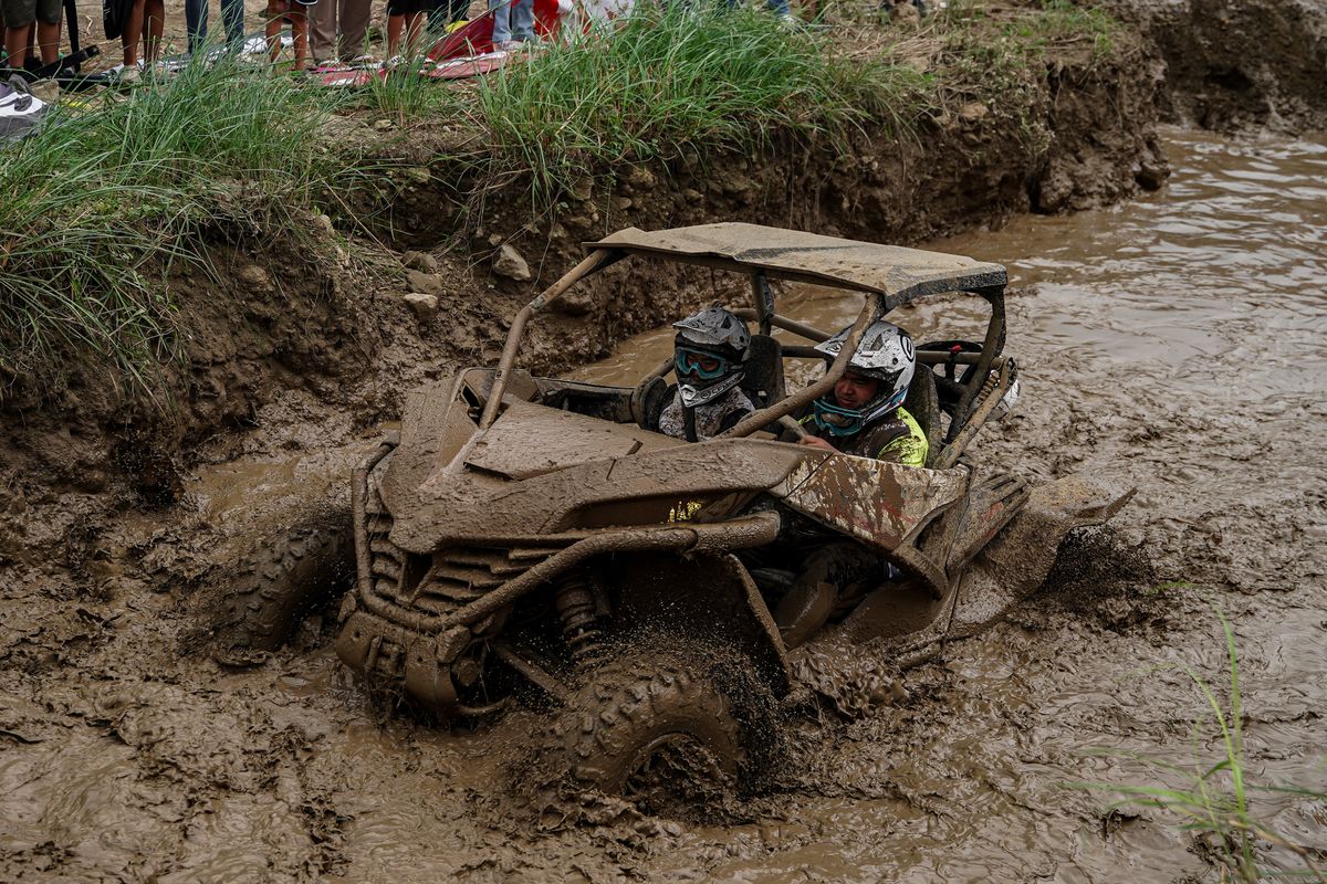 ATV side-by-side riding through deep muddy terrain off-road