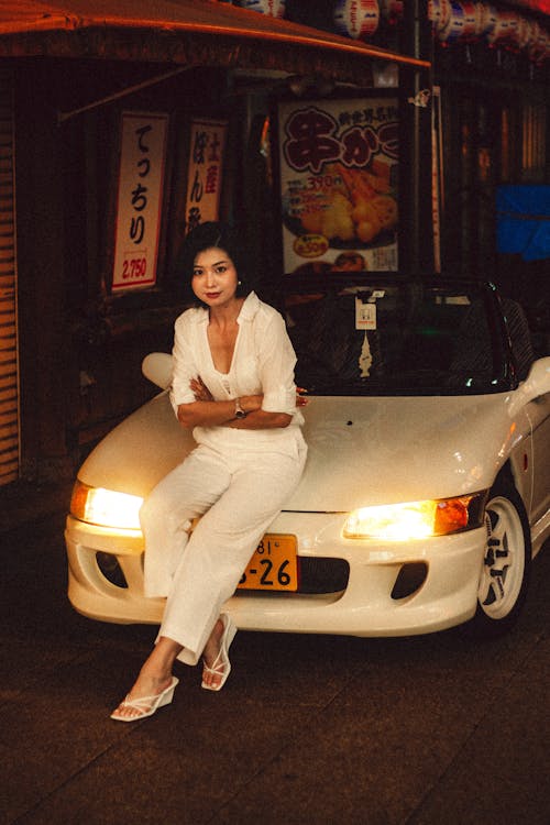 Free Stylish Woman Posing on Convertible at Night Stock Photo