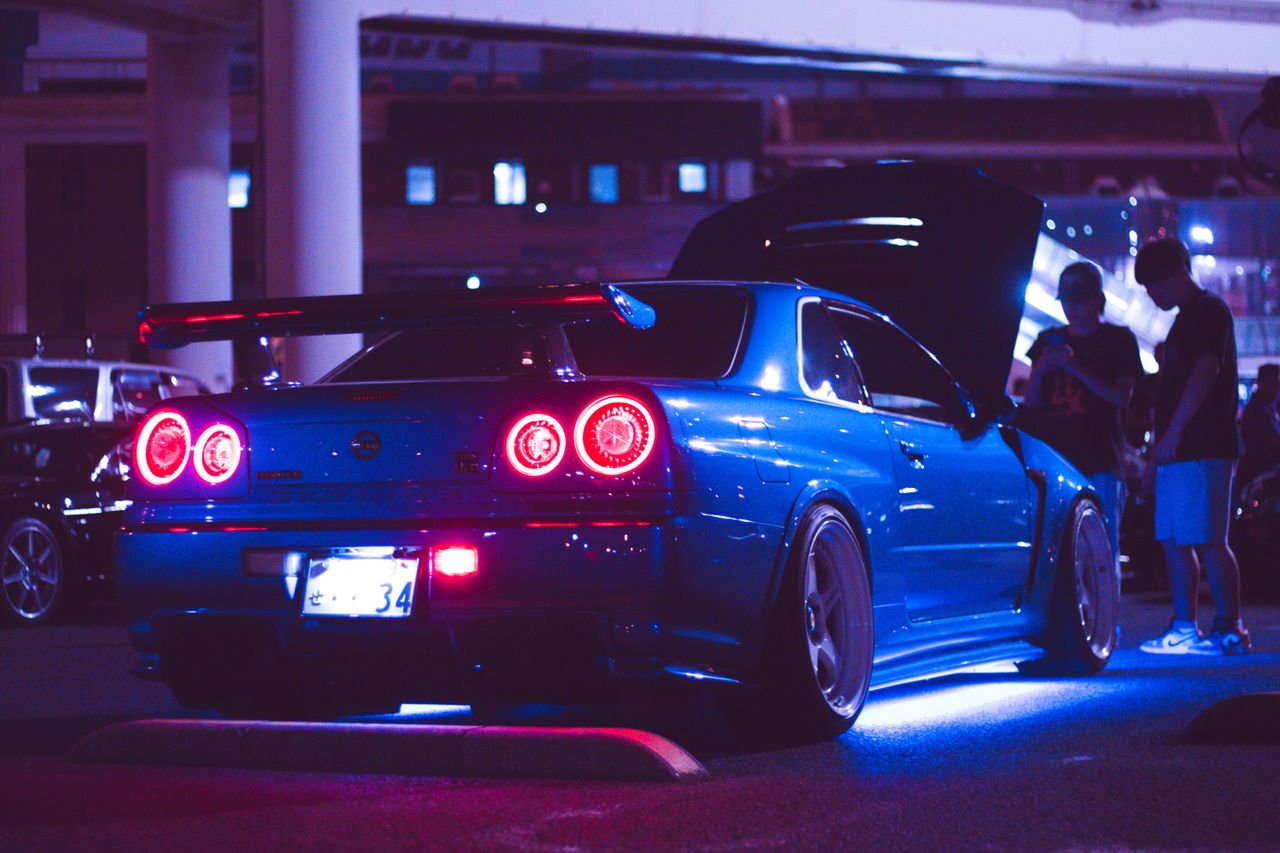a blue sports car with neon lights parked at night in an urban setting