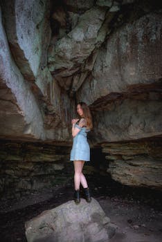 Young woman standing in a scenic rocky cave, showcasing natural beauty and adventure.
