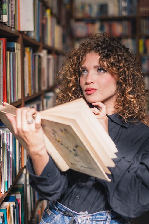 Photo of a Woman Holding a Book In Library