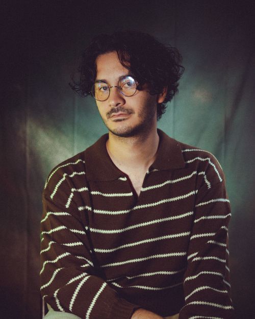 Free Man with glasses in a striped sweater against a dark backdrop. Stock Photo