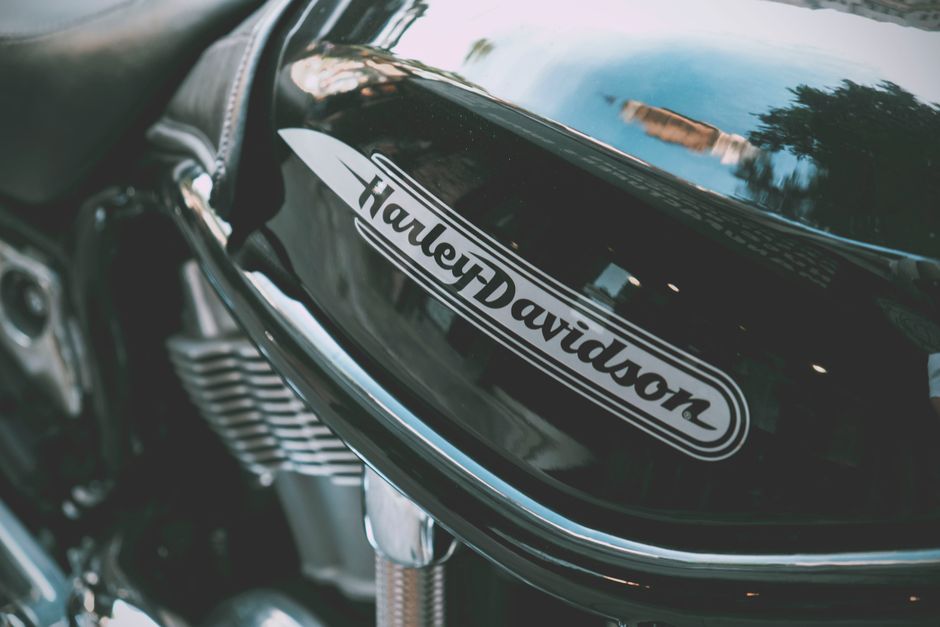 Detailed view of a shiny Harley Davidson motorcycle tank with reflections outdoors.