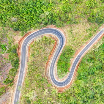 壮丽的鸟瞰图展现了印度尼西亚西爪哇蜿蜒道路在郁郁葱葱的绿色植物中穿行的景象