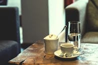木桌上放着浓缩咖啡杯、糖罐和水杯，环境很温暖