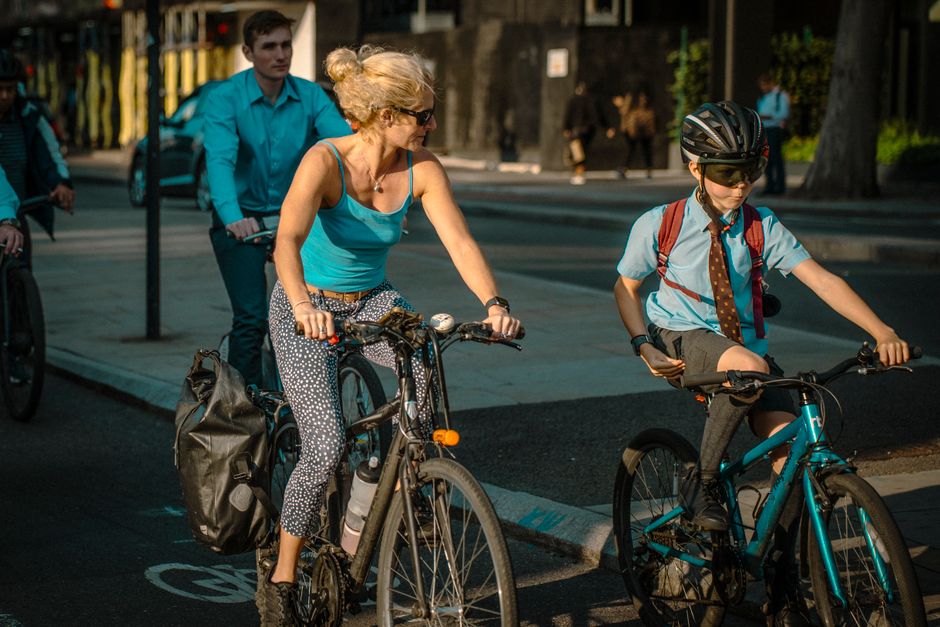 Group of people cycling on a sunny day in busy London streets, promoting eco-friendly commuting.