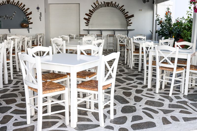 Café en terrasse avec chaises blanches sur un dallage de pierre, Naxos