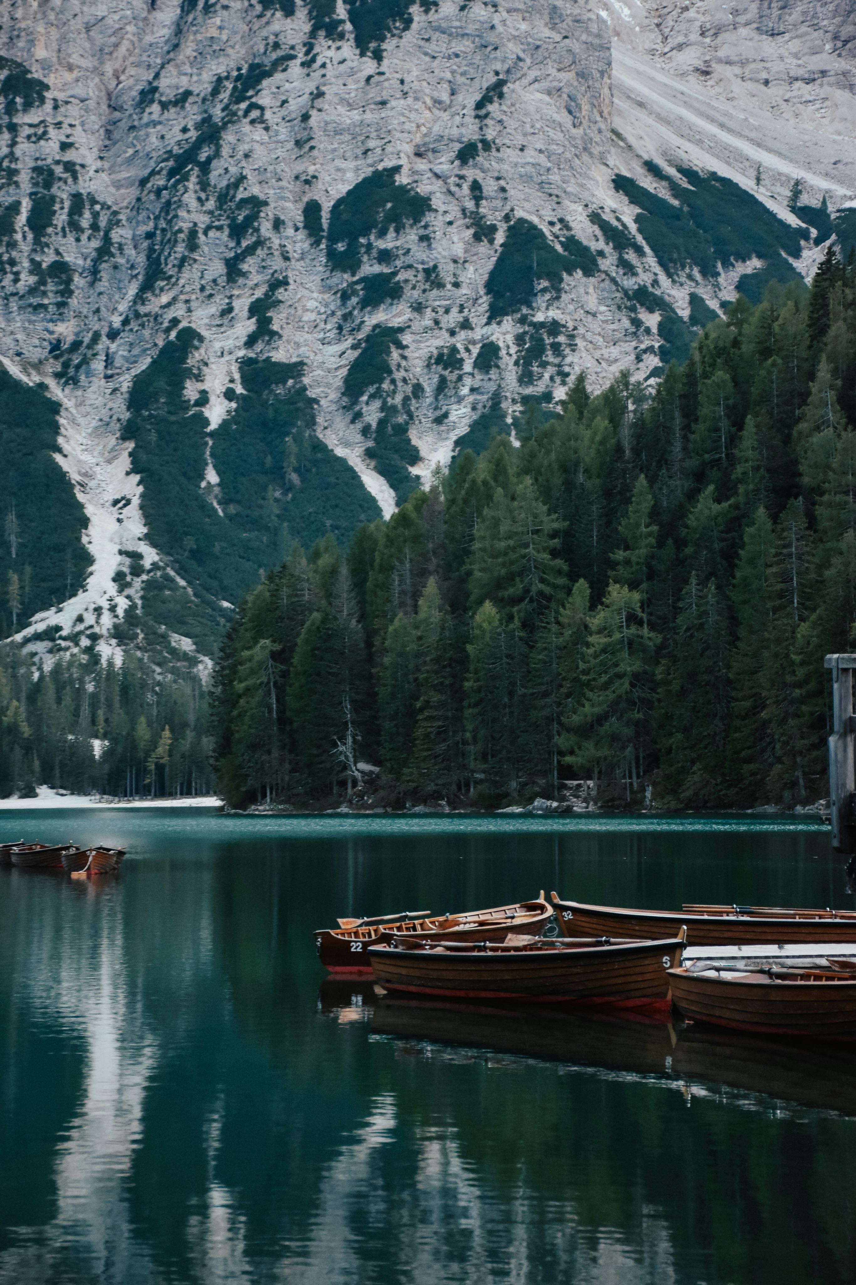 Serene mountain lake with wooden boats and lush green forest.