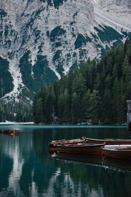 Serene mountain lake with wooden boats and lush green forest.