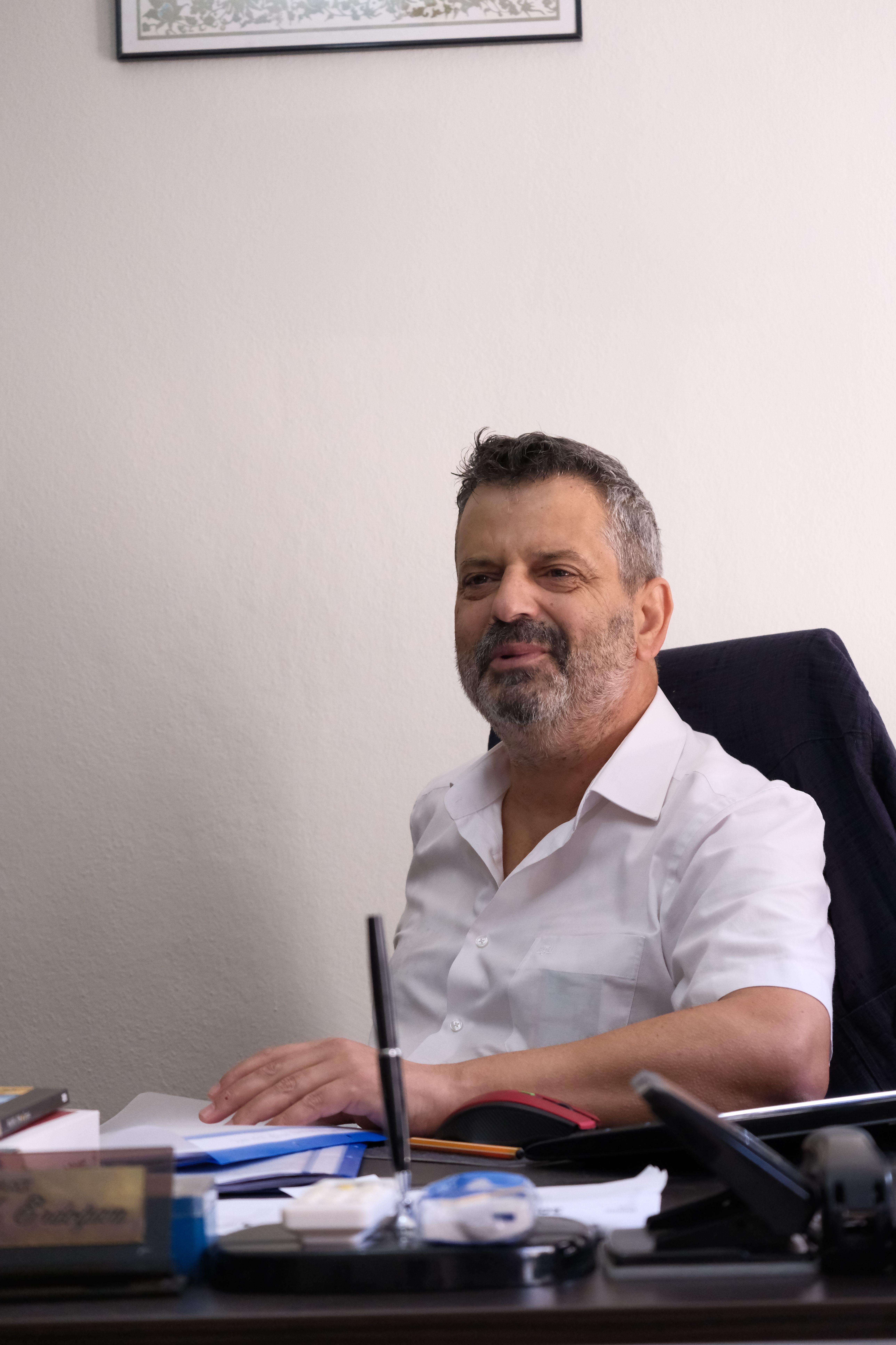 Businessman sitting at desk in an office, looking confident and engaged.