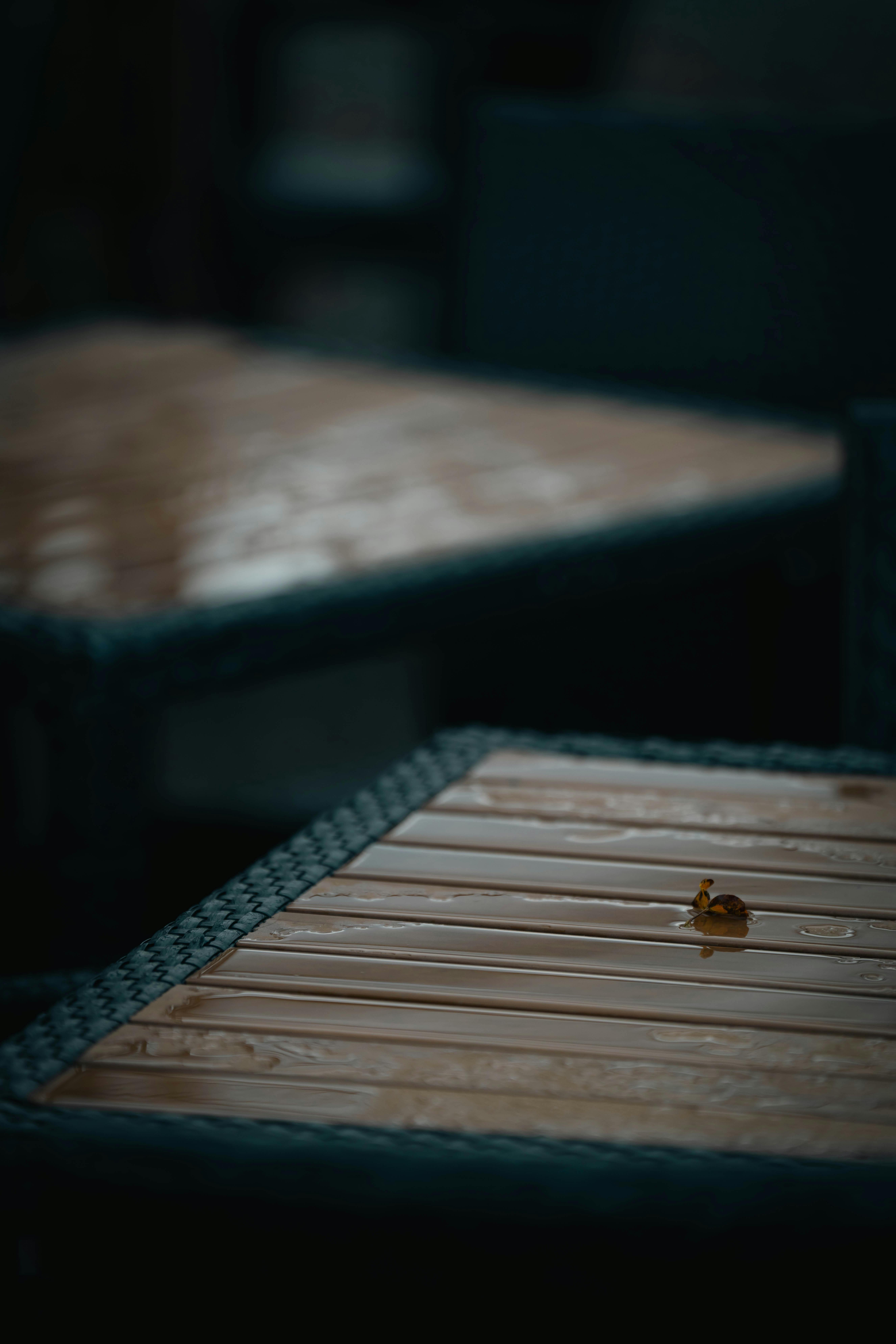 Gratuit Gros plan d'une goutte de pluie sur une table en bois extérieure avec une atmosphère maussade. Photos