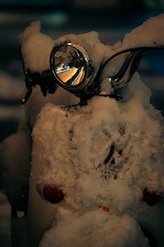 Close-up of a snow-covered vintage scooter highlighting the winter season.
