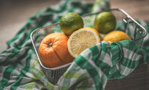 Free A vibrant display of citrus fruits in a metal basket on a green checkered cloth, evoking freshness. Stock Photo
