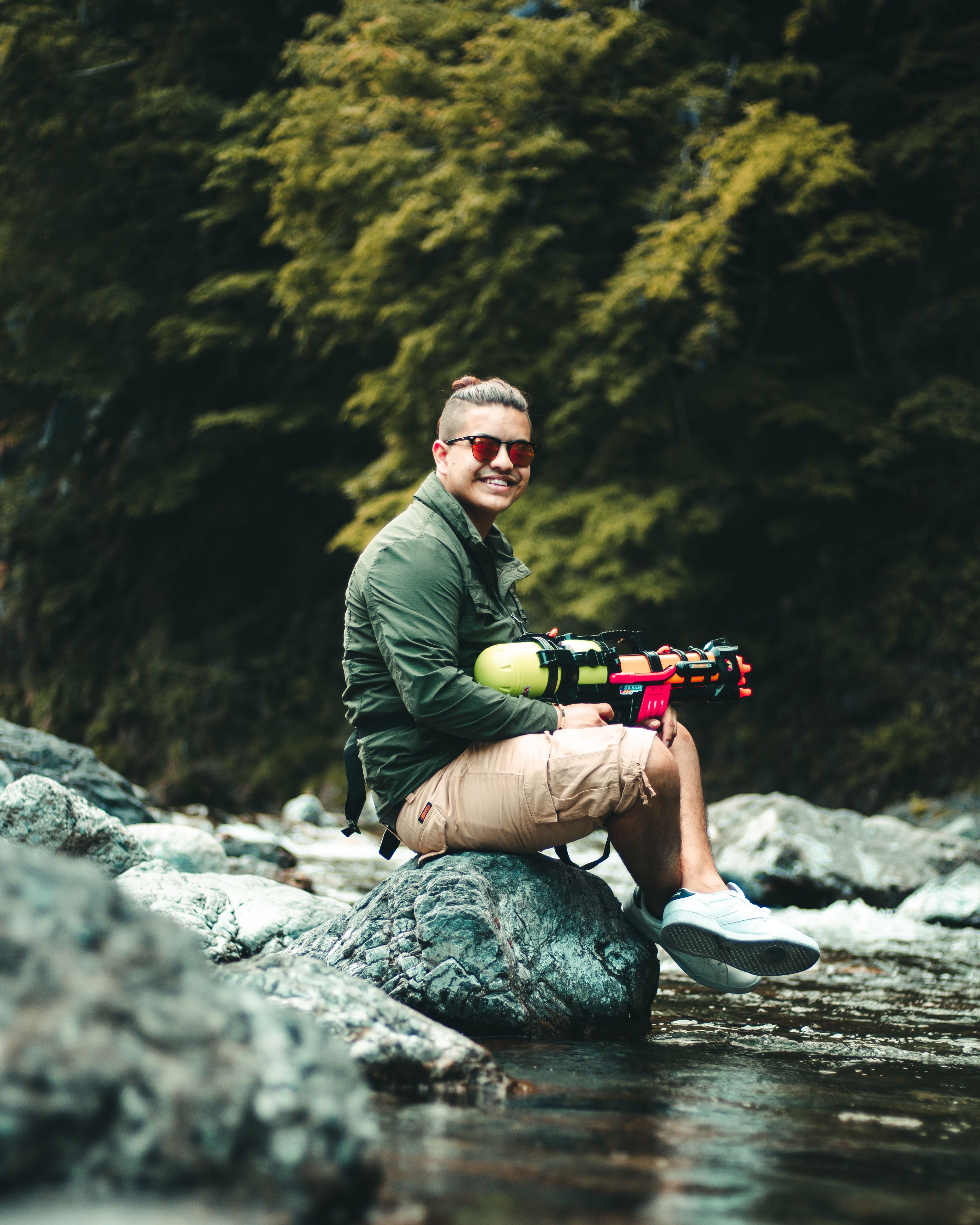 A young man enjoying leisure time by a river in Okutama, Tokyo with a water gun.