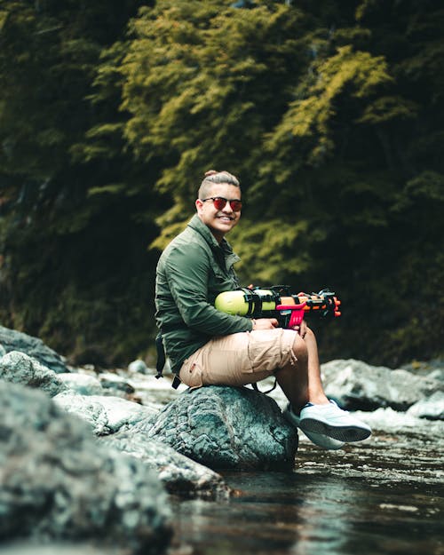 Man With A Toy Gun Sitting on A Rock Boulder