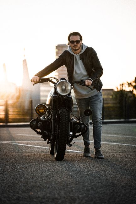 A man in casual wear stands by his motorcycle during sunset in Eindhoven.