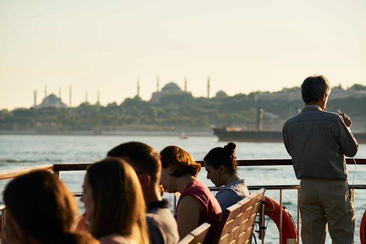 Man Standing Next To People Seated On Benches