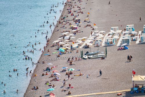 Free Crowded Antalya beach with sunbathers, umbrellas, and turquoise water, ideal summer destination. Stock Photo