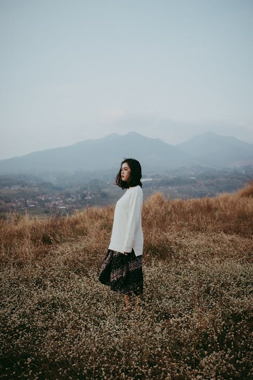 Free Woman in White Long-sleeved Top and Skirt Standing on Field Stock Photo