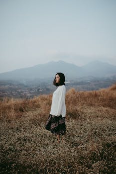 在印度尼西亚万隆，一个女人站在宁静的草地上，背景是山