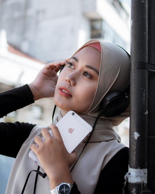 Woman Holding Iphone and Wearing Headphones