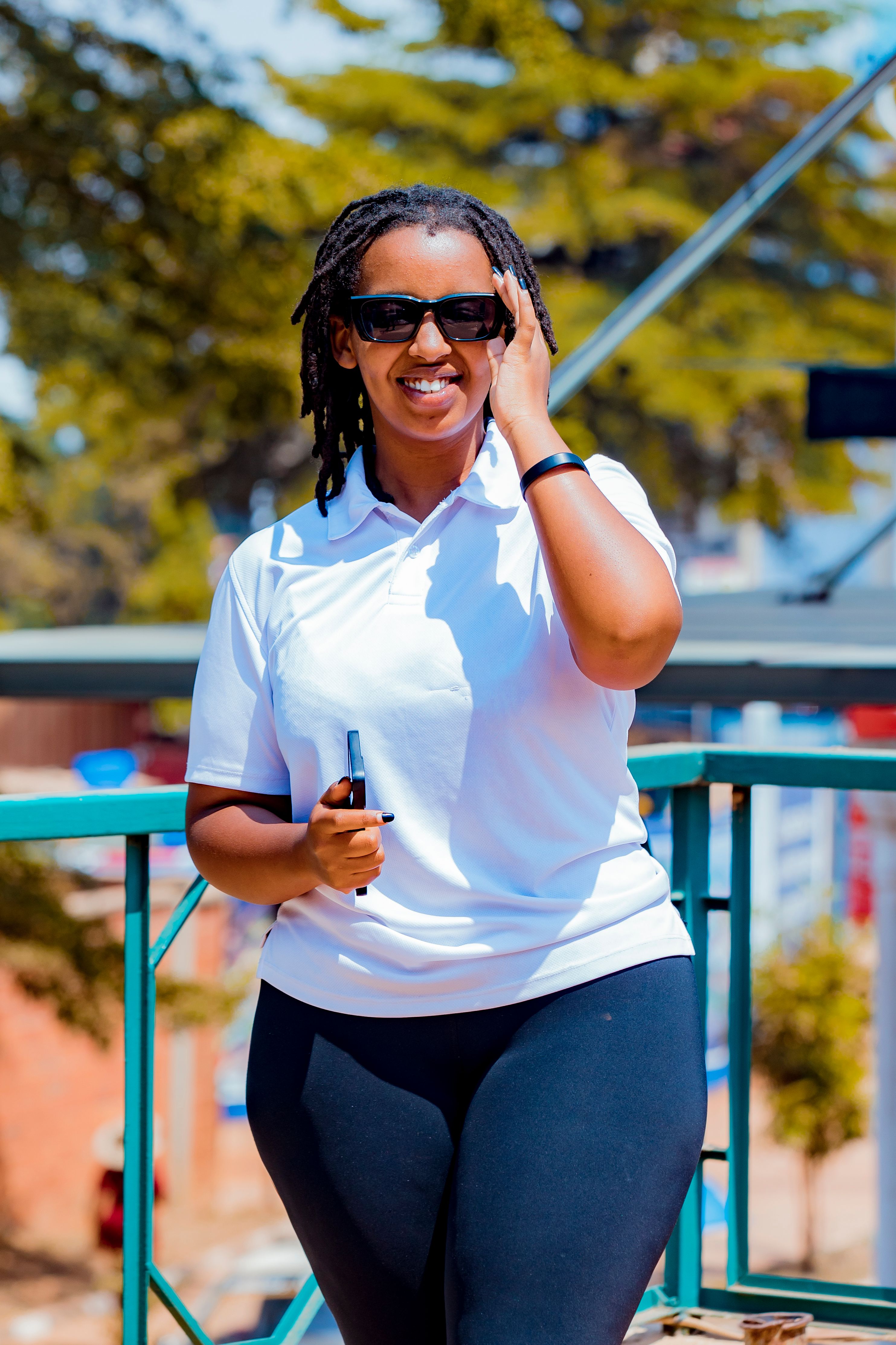 A cheerful woman in sunglasses enjoying a sunny day outside.