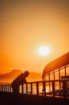 Silhouette of a person on a Seattle pier with a vibrant sunset sky.