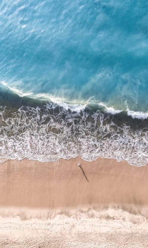 Аэрофотосъемка человека, стоящего на берегу моря