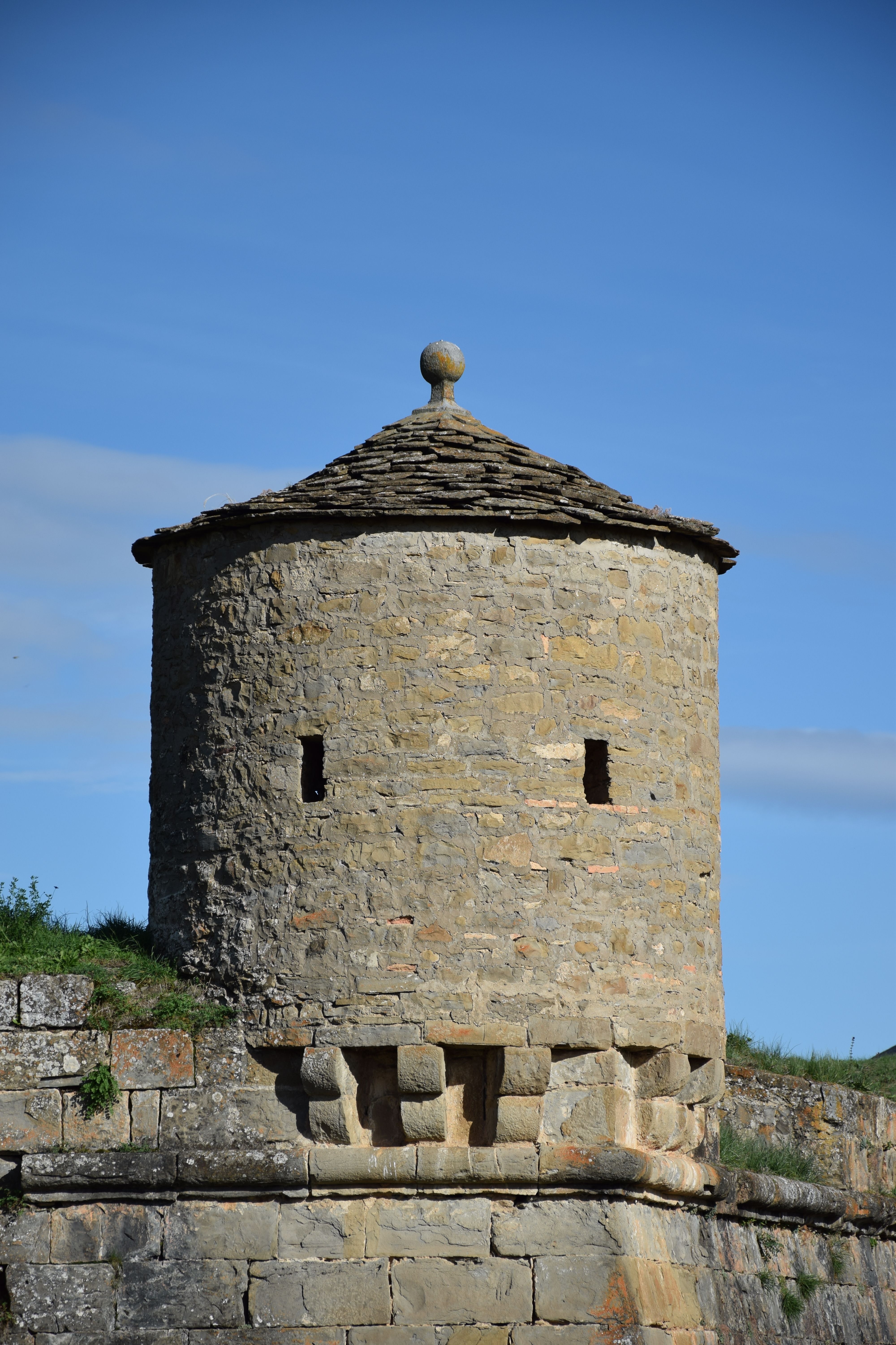 Stone round tower at Jaca's fortification under clear blue sky.