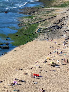 A lively summer beach scene at Santa Cruz, Portugal, with sunbathers and waves.