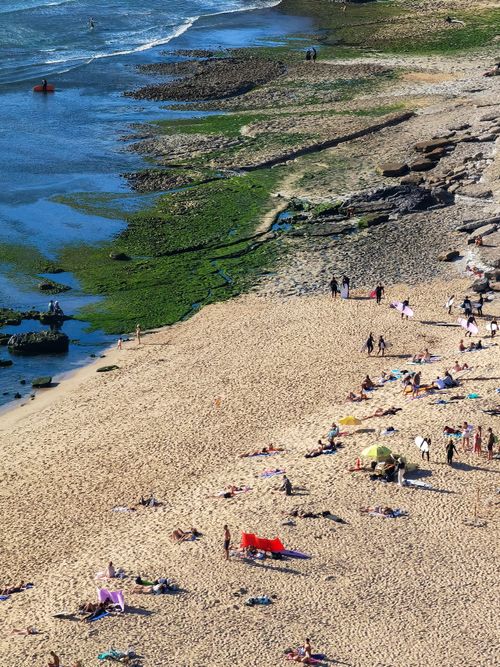 Free A lively summer beach scene at Santa Cruz, Portugal, with sunbathers and waves. Stock Photo