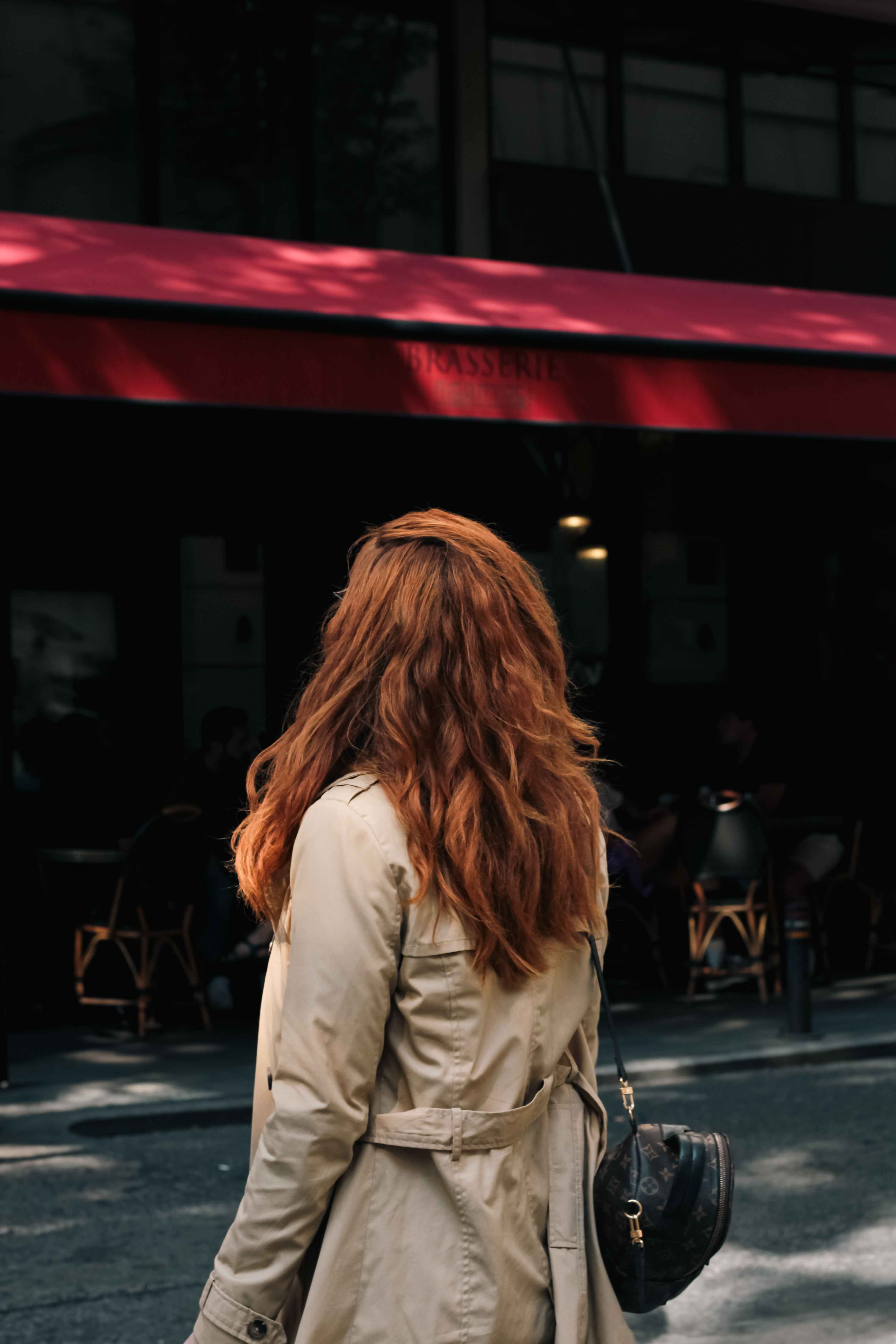 Woman in Beige Coat Walking Past Urban Cafe · Free Stock Photo
