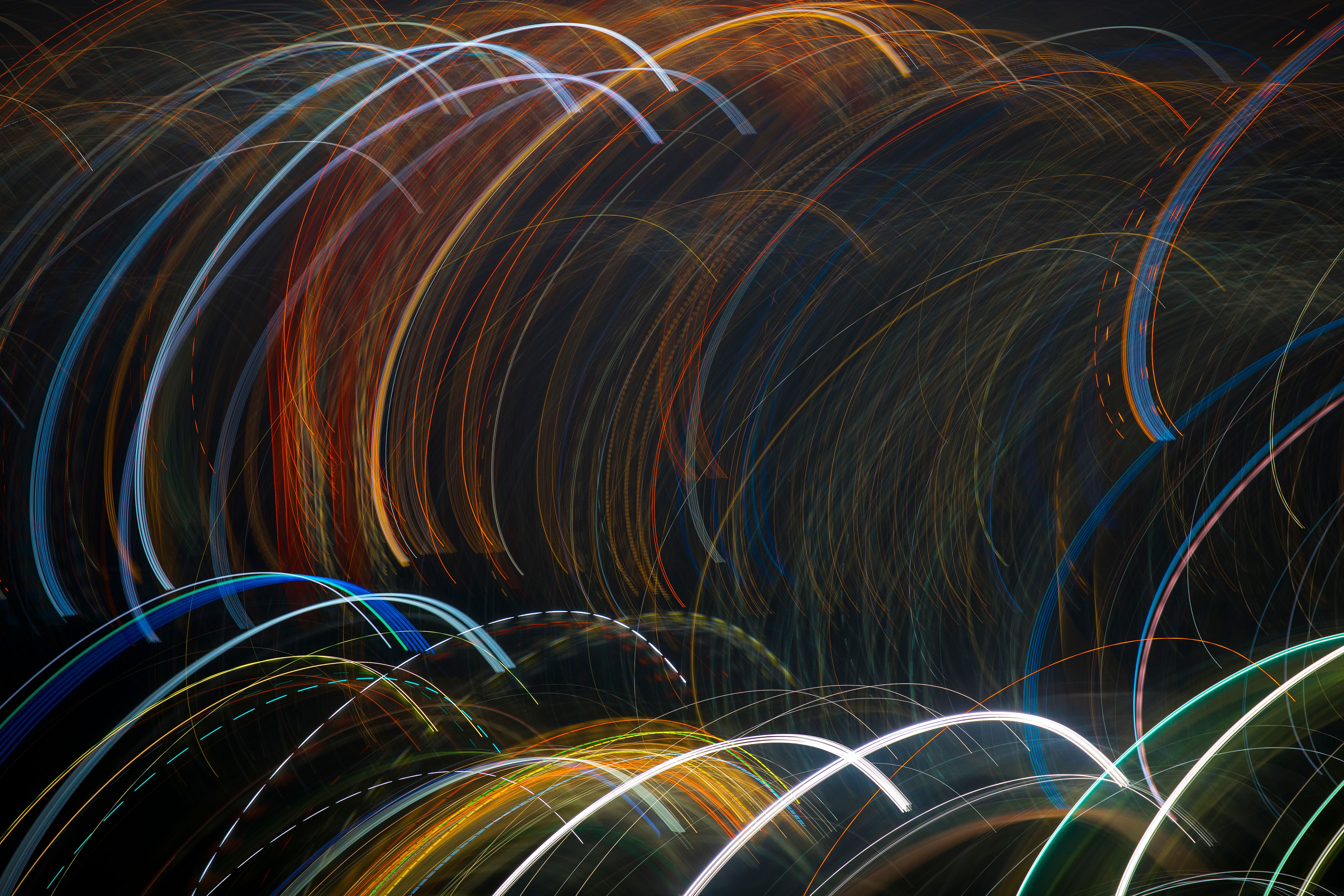 Colorful abstract light trails captured in motion during nighttime, creating a dynamic visual pattern.
