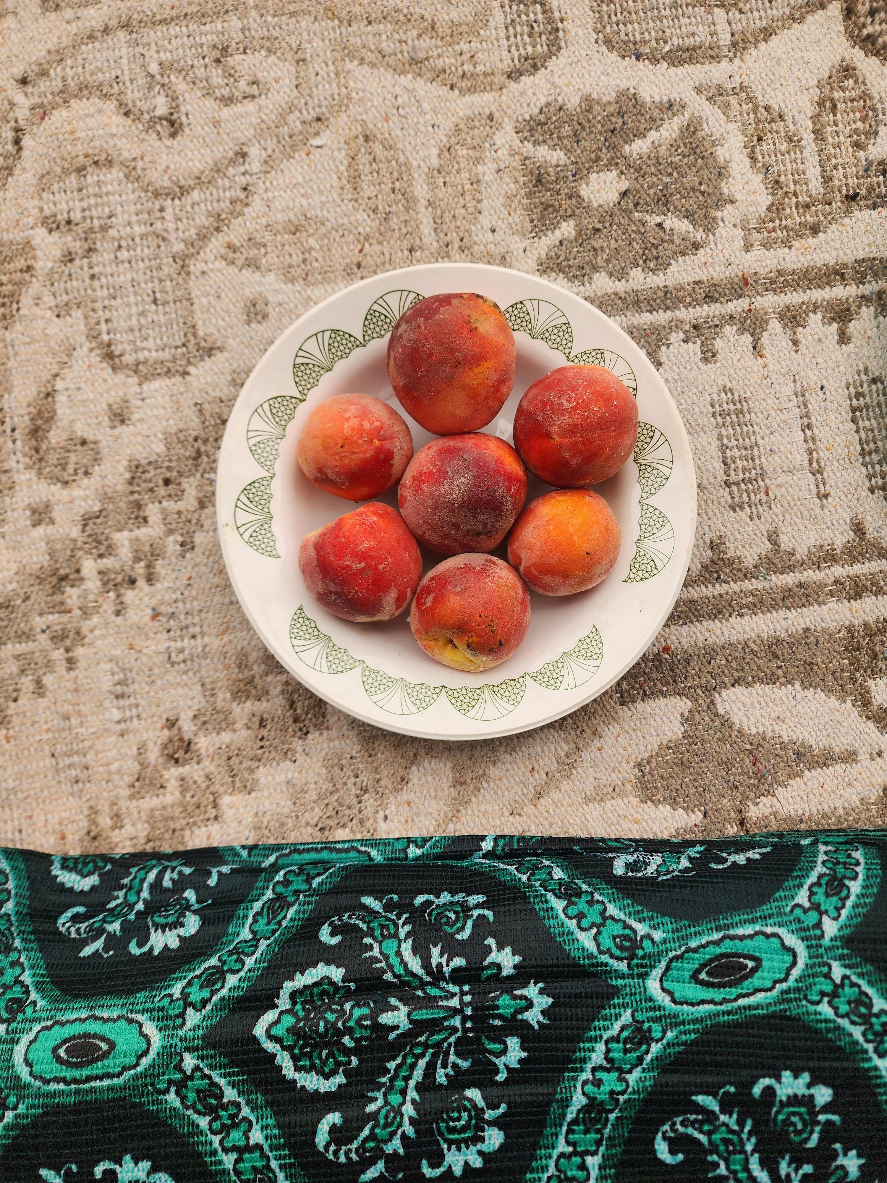 Gratis Toppvisning av modne fersken på en mønstret tallerken med tradisjonell tyrkisk teppebakgrunn. Arkivbilde