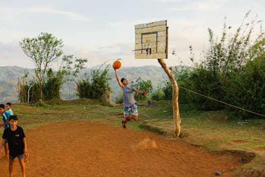 Young boy makes a jump shot on a rustic outdoor basketball court.