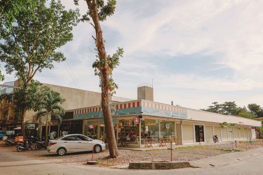 A cozy cafe with colorful storefront in a relaxing outdoor setting under a partly cloudy sky.