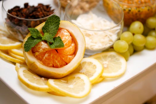 A vibrant assortment of citrus fruits with mint, grapes, and nuts on a platter.