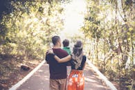 一个家庭在阳光明媚的公园小径上悠闲散步，展现出团结与爱