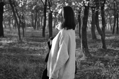 Free Black and white portrait of a woman in a sweater in a serene forest setting. Stock Photo