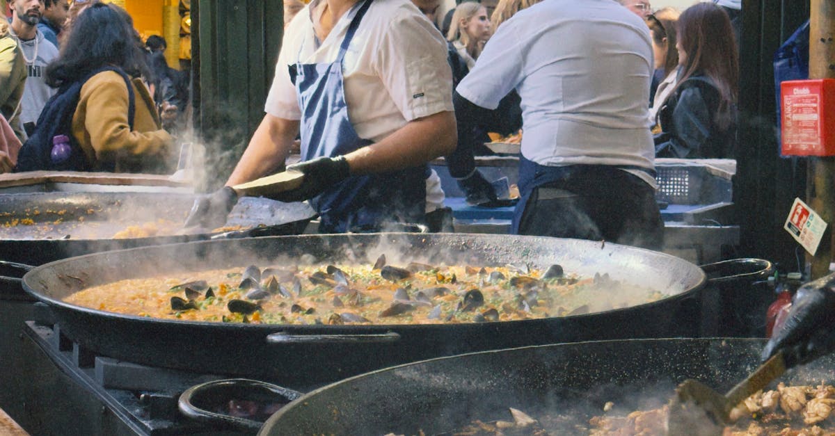 A steaming pan of traditional Spanish paella cooking over an open flame.