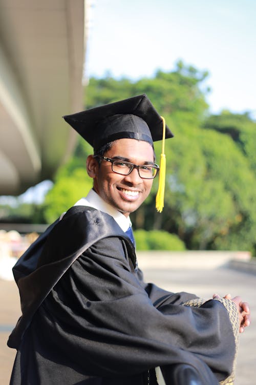 Free Man Wearing Black Graduation Gown and Cap Stock Photo