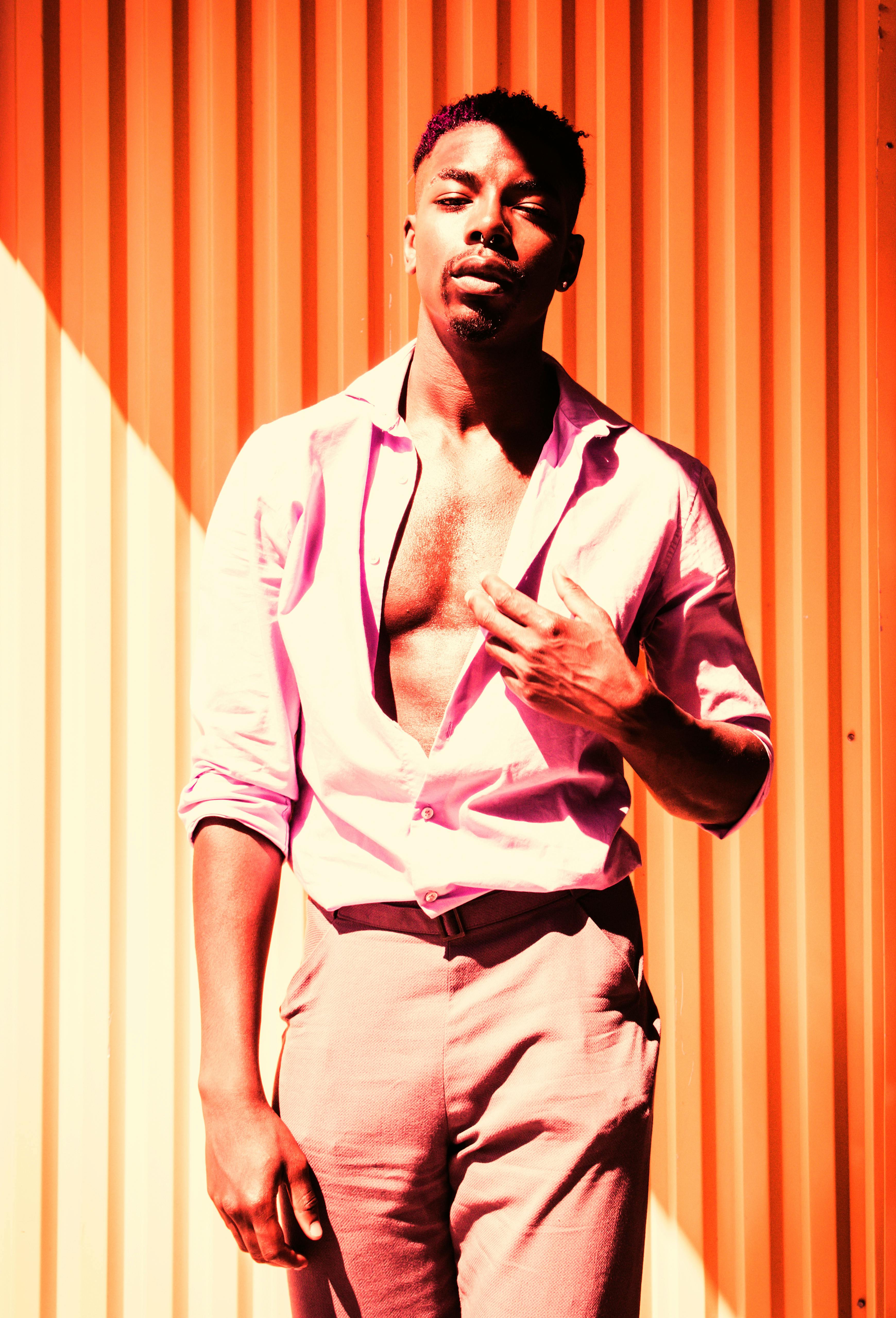 男模在阳光照射的墙壁上摆出时尚姿势，与大胆的阴影相映成趣