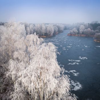从空中俯瞰，冬季霜冻的美景中，冰封的湖泊与白雪覆盖的树木尽收眼底