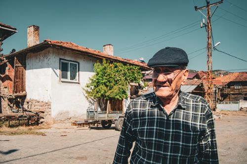 Free An elderly man in a checkered shirt enjoys a sunny day in Sındırgı village, Türkiye. Stock Photo