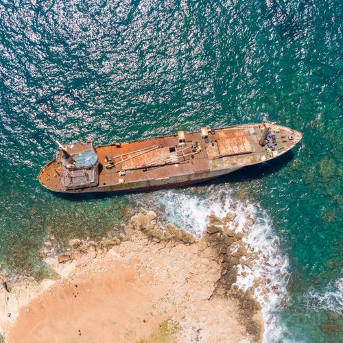 Free Drone shot of a shipwreck on the coast of Paphos, Cyprus, surrounded by clear turquoise waters. Stock Photo