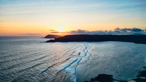 Free A breathtaking sunset over a serene coastal landscape with gentle waves. Stock Photo