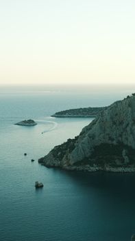 Calm sea view with rugged cliffs and small islands under soft lighting.